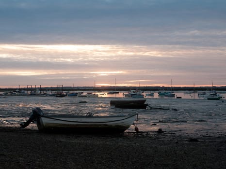 sunset over moored private wooden boats on coastline shore; essex; england; uk