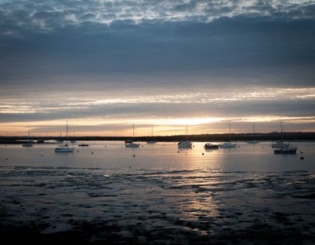 sunset over river estuary west mersea essex seafront coast boats; essex; england; uk
