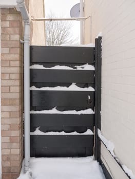 closed black gate with metal bolt with snow; essex; england; uk