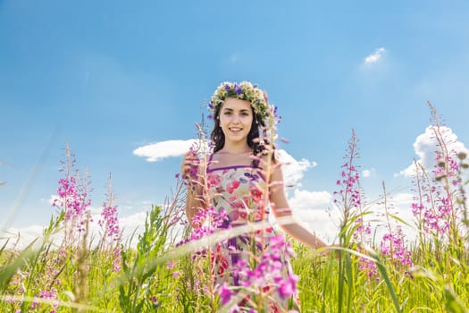 Portrait of the beautiful girl in the field in flowers