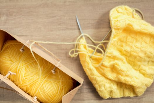 Light yellow knitting wool and knitting needles on wooden background. Top view.copy space. Knitted fabric and yarn on a wooden surface.