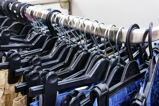 Closeup shot of row of pants and jeans on the hangers in modern clothing store