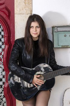 Close view of a beautiful young woman with classic guitar on the streets of the city.