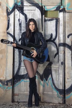 Close view of a beautiful young woman with classic guitar on the streets of the city.