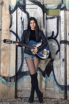 Close view of a beautiful young woman with classic guitar on the streets of the city.