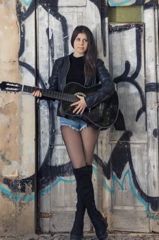 Close view of a beautiful young woman with classic guitar on the streets of the city.