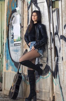 Close view of a beautiful young woman with classic guitar on the streets of the city.