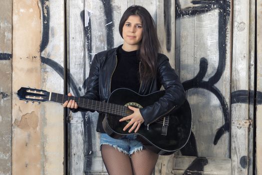 Close view of a beautiful young woman with classic guitar on the streets of the city.