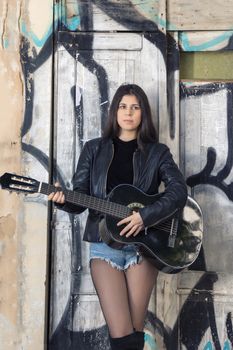 Close view of a beautiful young woman with classic guitar on the streets of the city.