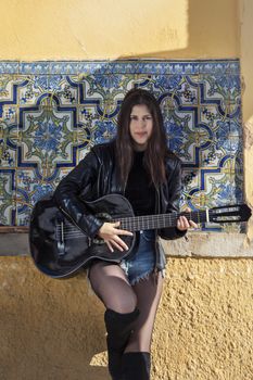 Close view of a beautiful young woman with classic guitar on the streets of the city.