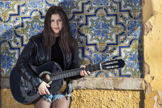 Close view of a beautiful young woman with classic guitar on the streets of the city.