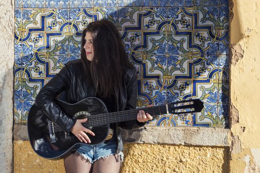 Close view of a beautiful young woman with classic guitar on the streets of the city.