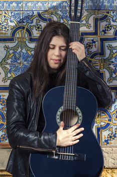 Close view of a beautiful young woman with classic guitar on the streets of the city.