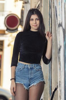 Close view of a beautiful young woman with short blue jeans on the streets of the city.