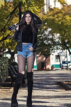 Close view of a beautiful young woman with classic guitar on a garden in the city.