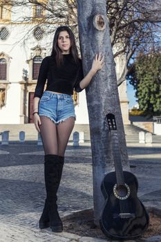 Close view of a beautiful young woman with classic guitar on the streets of the city.