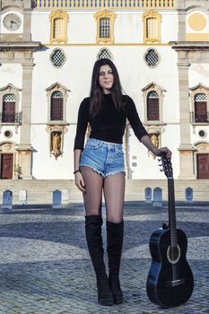 Close view of a beautiful young woman with classic guitar on the streets of the city.