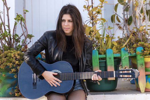 Close view of a beautiful young woman with classic guitar on the streets of the city.