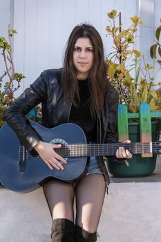 Close view of a beautiful young woman with classic guitar on the streets of the city.