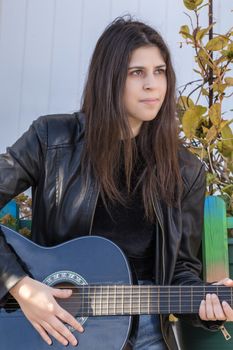 Close view of a beautiful young woman with classic guitar on the streets of the city.