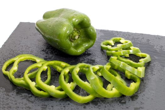 green bell peppers on a black stone of schist, wet and sliced.