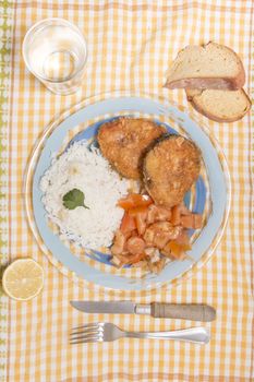 Fried hake fish with rice and tomato salad.