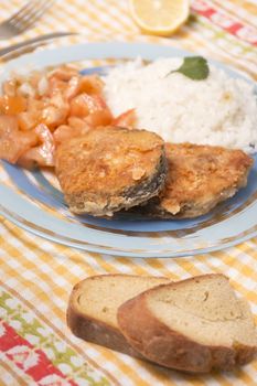 Fried hake fish with rice and tomato salad.