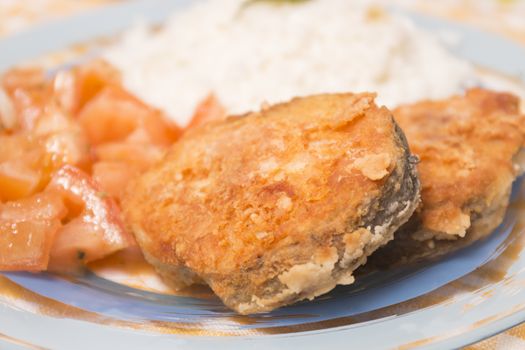 Fried hake fish with rice and tomato salad.