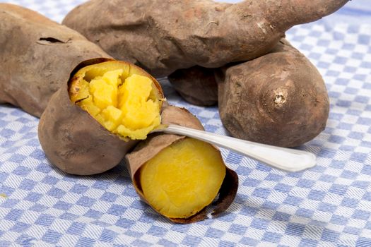 Cooked oven sweet potatoes on a table cloth fabric.