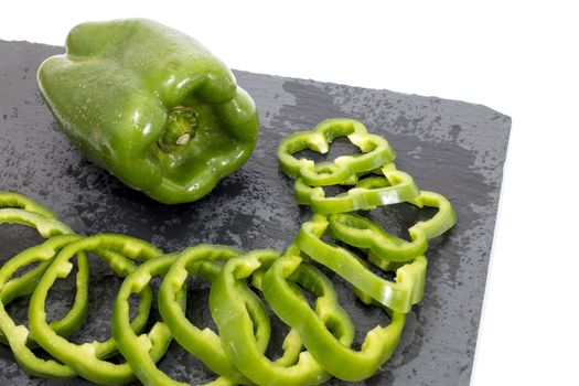 green bell peppers on a black stone of schist, wet and sliced.