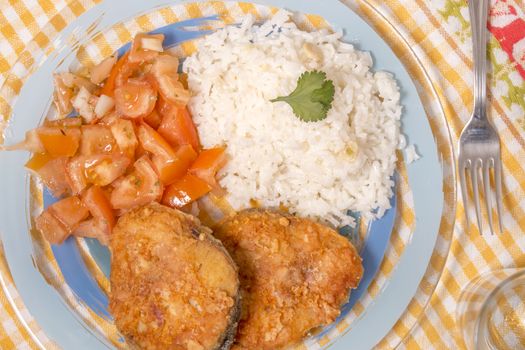 Fried hake fish with rice and tomato salad.