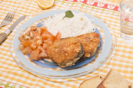 Fried hake fish with rice and tomato salad.