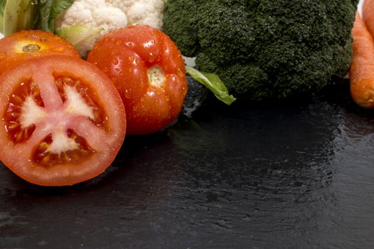 Mixed wet vegetables on top of a black slab of schist.