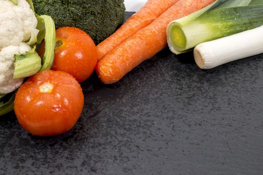 Mixed wet vegetables on top of a black slab of schist.