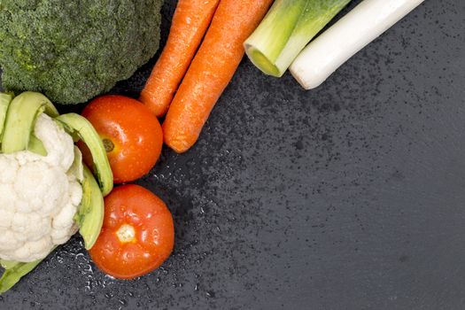 Mixed wet vegetables on top of a black slab of schist.