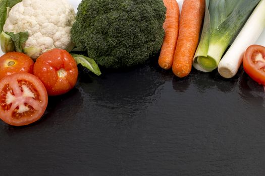 Mixed wet vegetables on top of a black slab of schist.