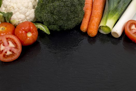 Mixed wet vegetables on top of a black slab of schist.