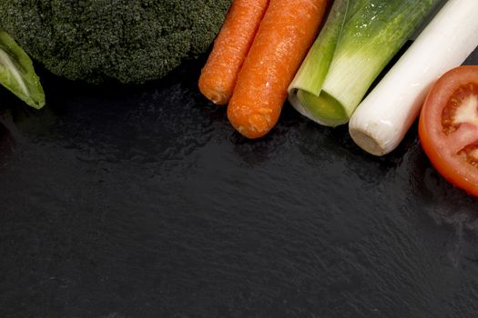 Mixed wet vegetables on top of a black slab of schist.