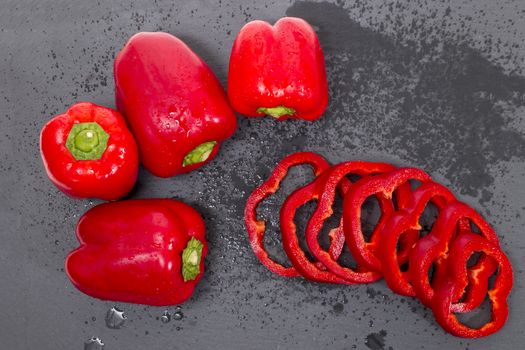 red bell peppers on a black stone of schist, wet and sliced.