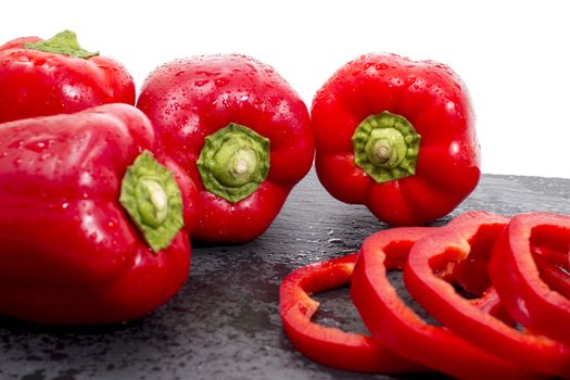 red bell peppers on a black stone of schist, wet and sliced.