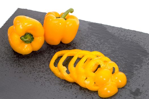 yellow bell peppers on a black stone of schist, wet and sliced.