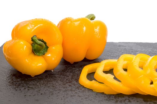 yellow bell peppers on a black stone of schist, wet and sliced.