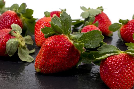 Red tasty strawberries on a black slab of schist.