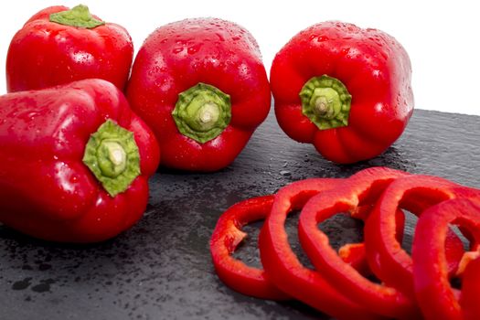 red bell peppers on a black stone of schist, wet and sliced.