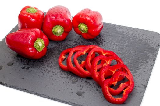 red bell peppers on a black stone of schist, wet and sliced.
