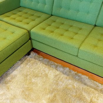Bright green corner sofa on fluffy rug. Contemporary furniture.