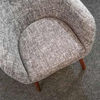 Stylish gray armchair on carpet floor. Comfortable furniture.