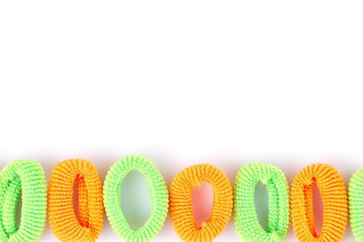 Green and orange soft hair bands are lined with a line on a white background