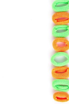 Green and orange soft hair bands are lined with a line on a white background
