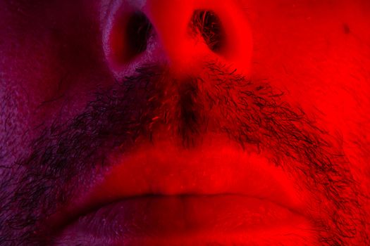 Macro close up on man mouth with serious facial expression. Portrait of expressionless young man.
